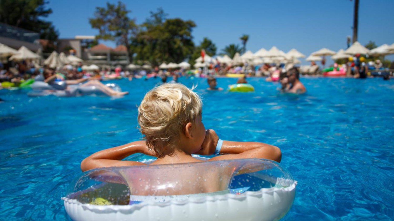 Dziecko kąpie się w basenie na all inclusive.