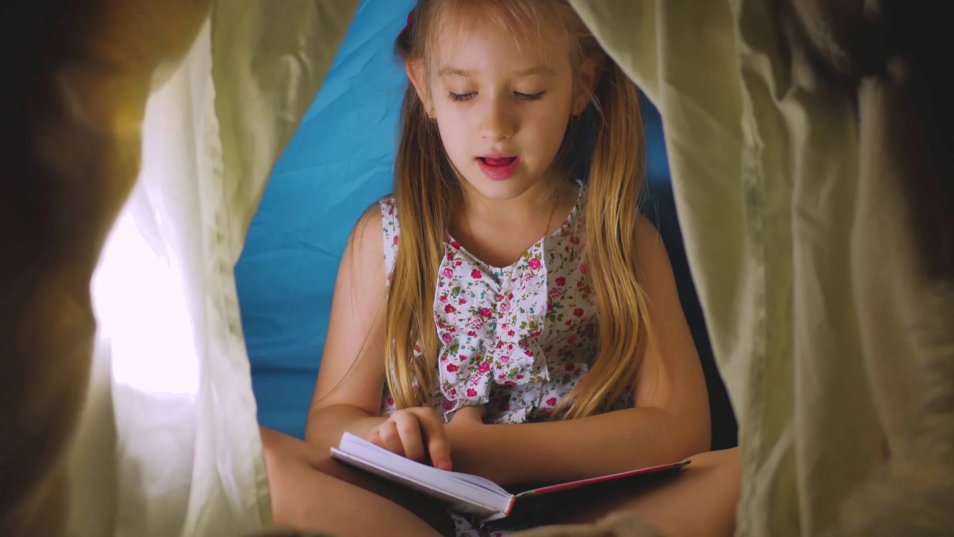 dziewczynka w wieku szkolnym czyta w namiocie książkę