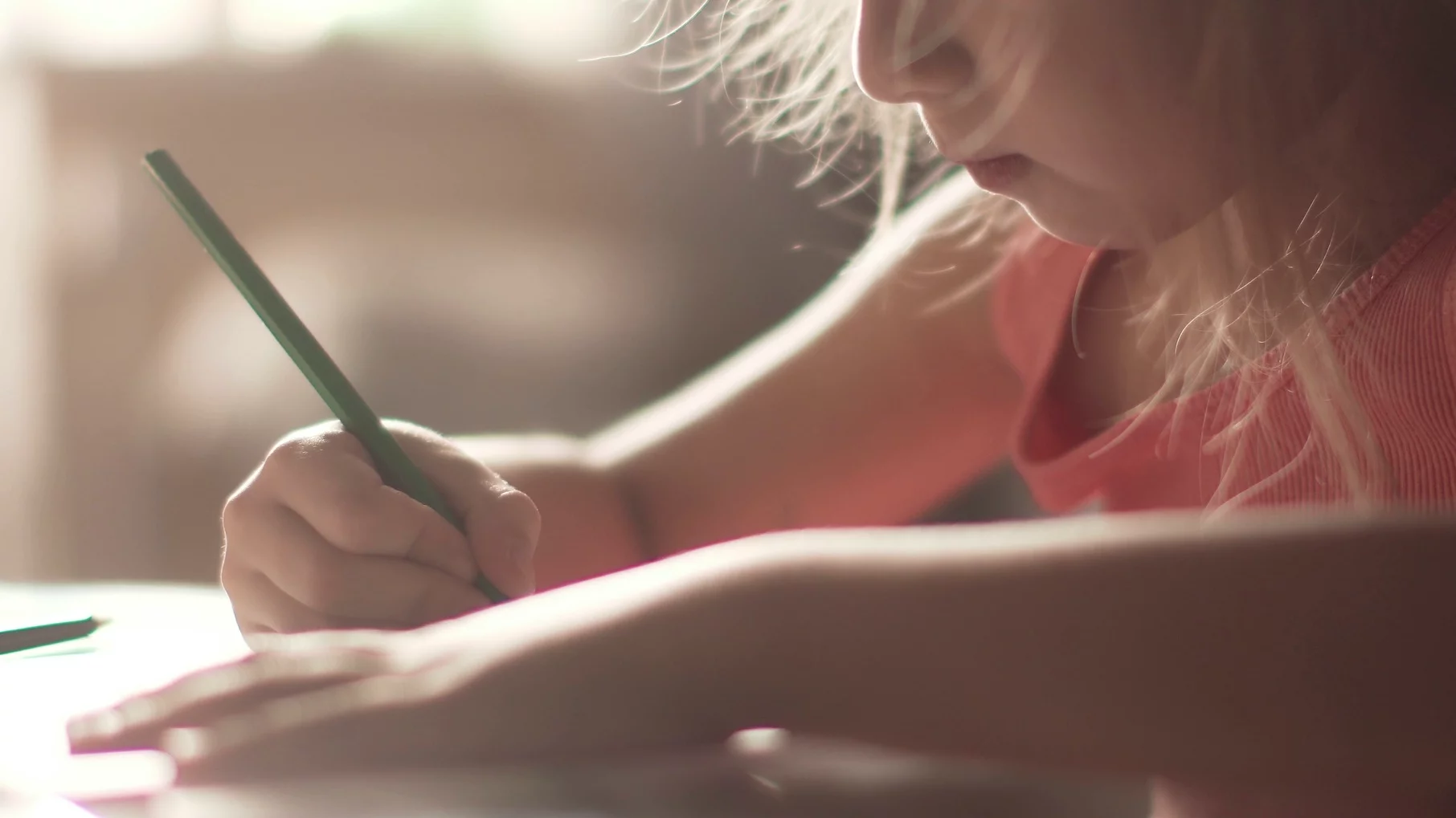 Na zdjęciu dziewczyna rysuje coś przy stoliku w przedszkolu
