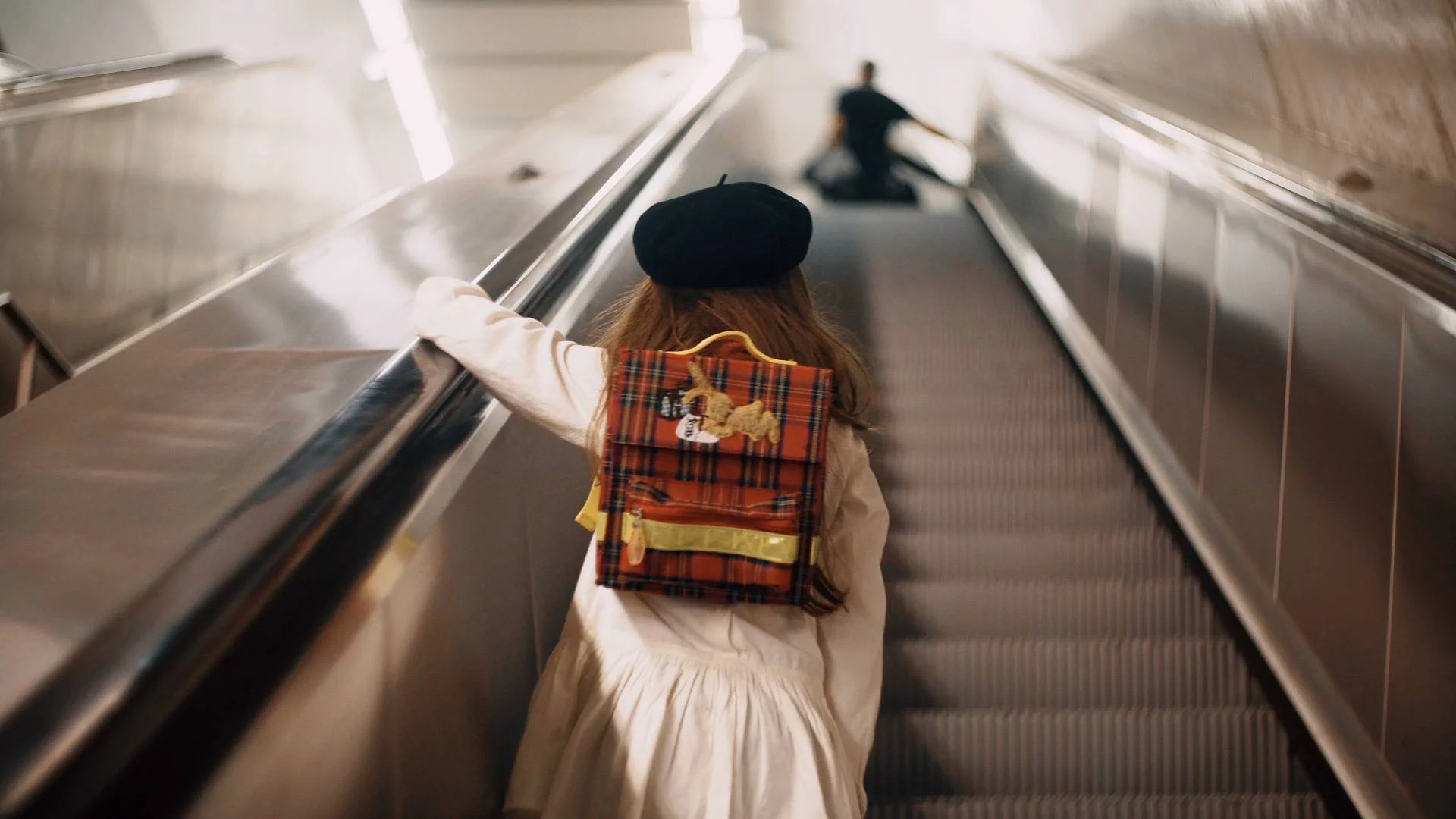 dziewczynka z plecakiem jedzie ruchomymi schodami dziewczynka z plecakiem jedzie ruchomymi schodami