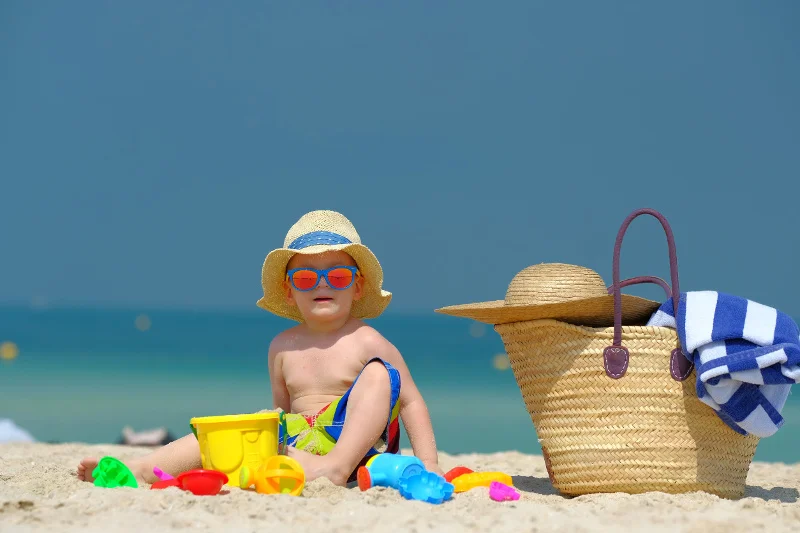 Wypoczywając na skąpanej w słońcu dubajskiej plaży, należy pamiętać o okularach przeciwsłonecznych i odpowiednim nakryciu głowy dla malucha