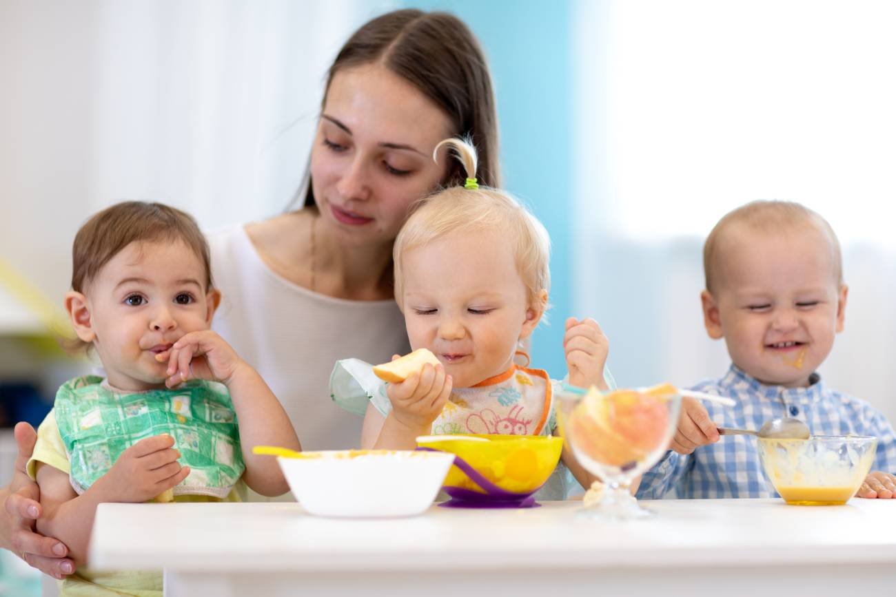 Opiekunka w żłobku pilnuje dzieci jedzących posiłek. Opiekunka w żłobku pilnuje dzieci jedzących posiłek.