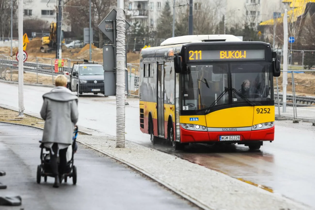 Matka z wózkiem idzie na przystanek autobusowy.