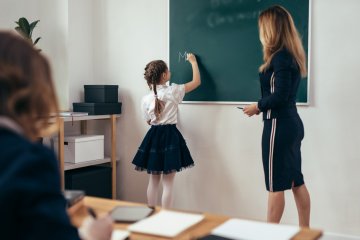 Dziewczynka odpowiada przy tablicy na lekcji języka polskiego.