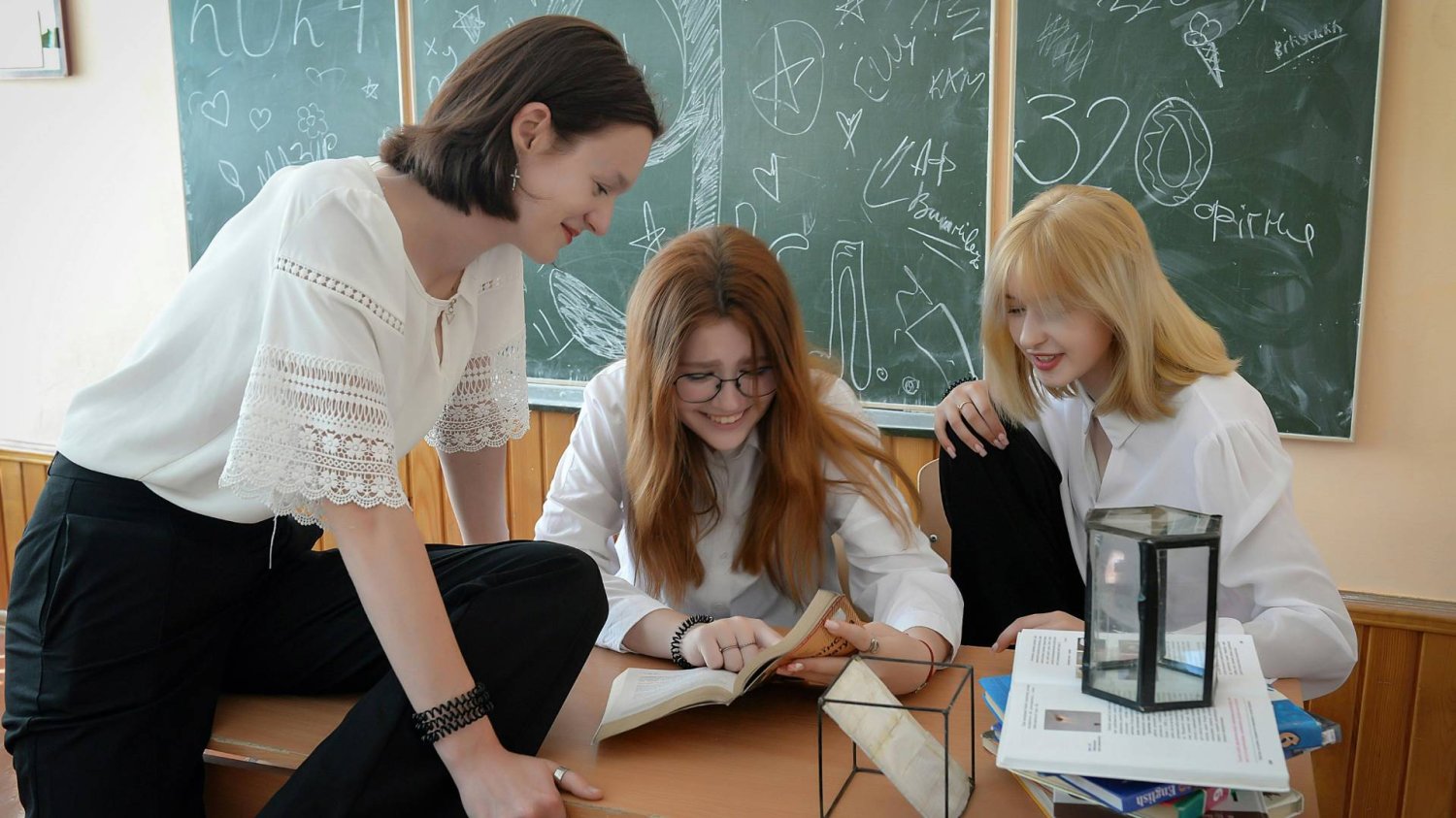 uczennice w klasie od matematyki wspólnie przeglądają podręcznik uczennice w klasie od matematyki wspólnie przeglądają podręcznik