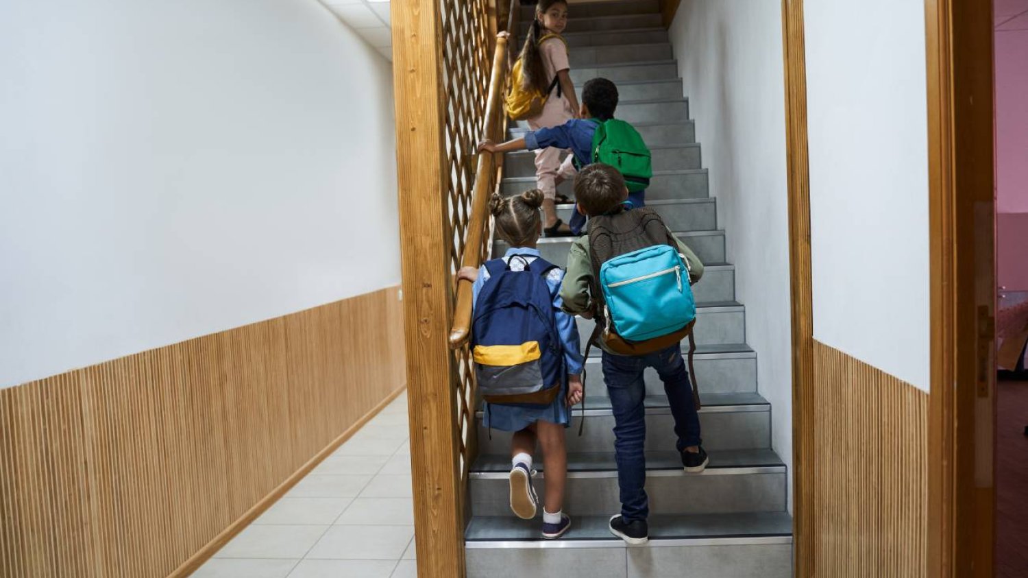 Uczniowie wchodzący po schodach na szkolnym korytarzu.