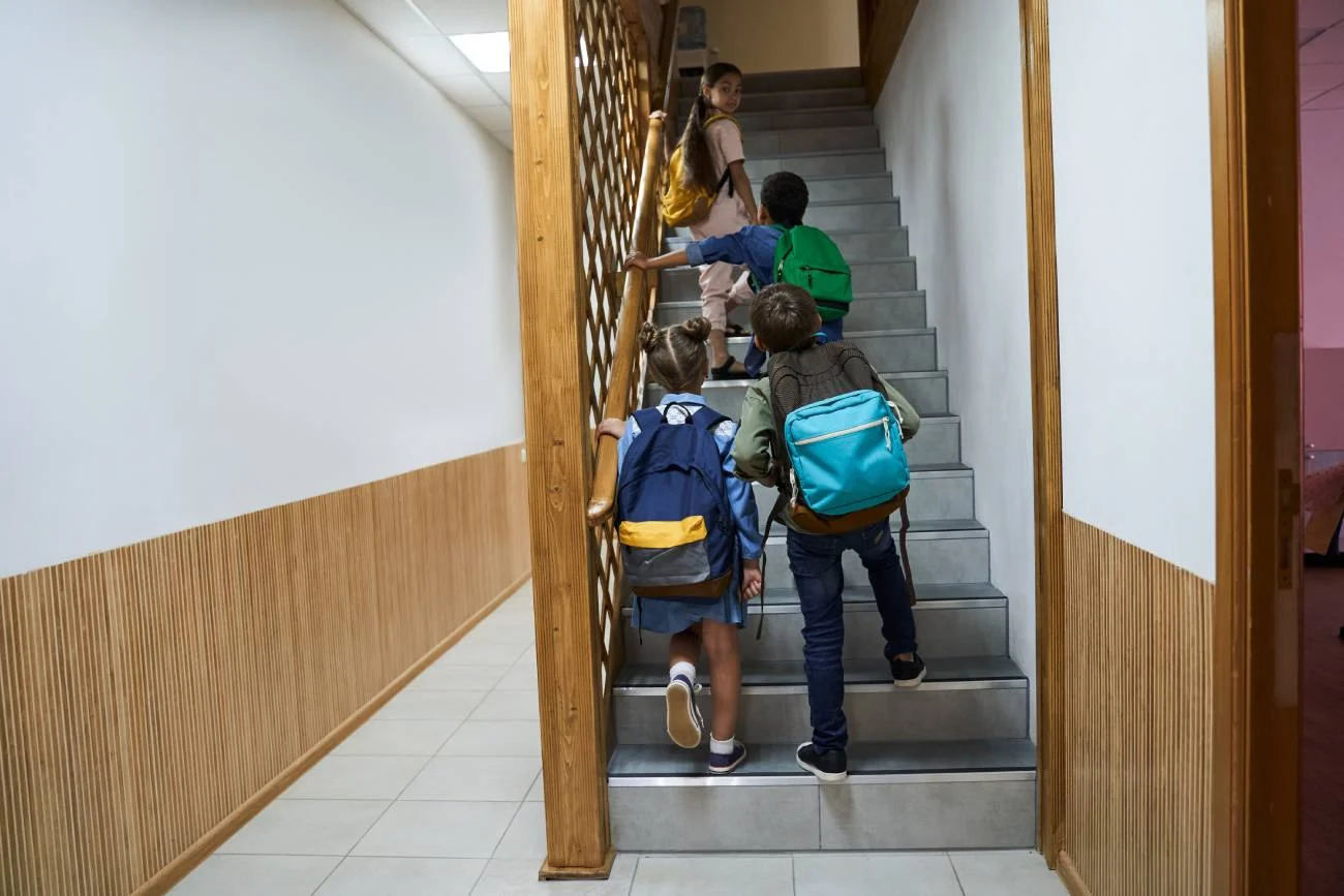 Uczniowie wchodzący po schodach na szkolnym korytarzu.