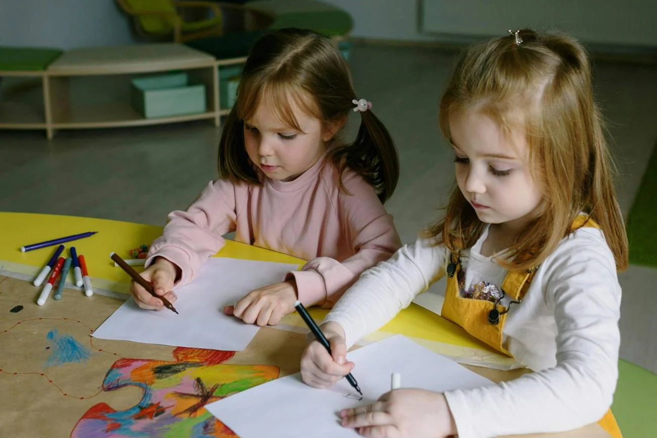 dziewczynki siedzą i rysują przy stoliku