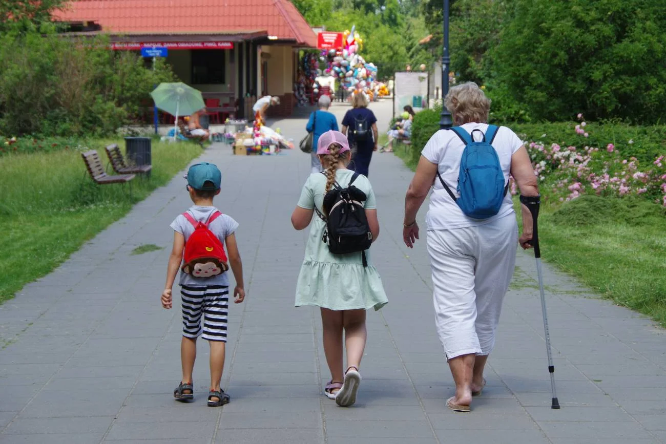 Babcia z wnukami na spacerze w parku.
