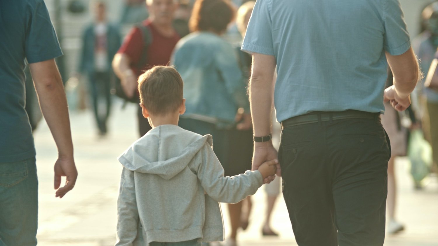 Życiowe prawdy rodziców, które dziś już się nie sprawdzają. Na zdjęciu jest tłum ludzi na ulicy, a wśród niego ojciec lub dziadek trzyma syna lub wnuka za rękę.