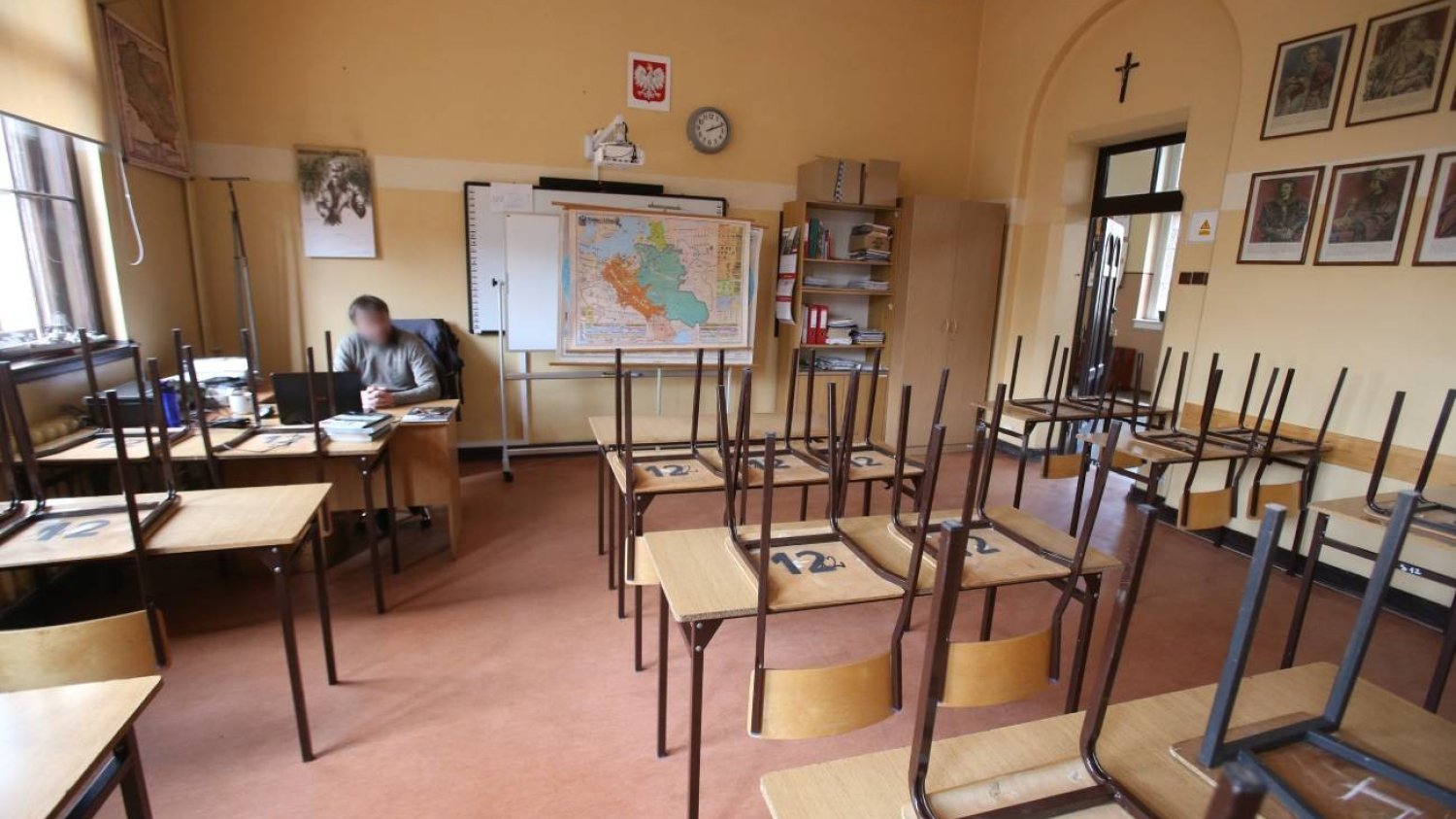 Nauczyciel siedzi w pustej klasie lekcyjnej.
