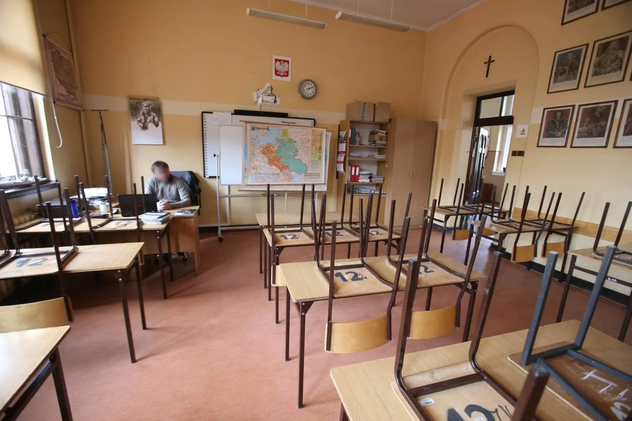 Nauczyciel siedzi w pustej klasie lekcyjnej.