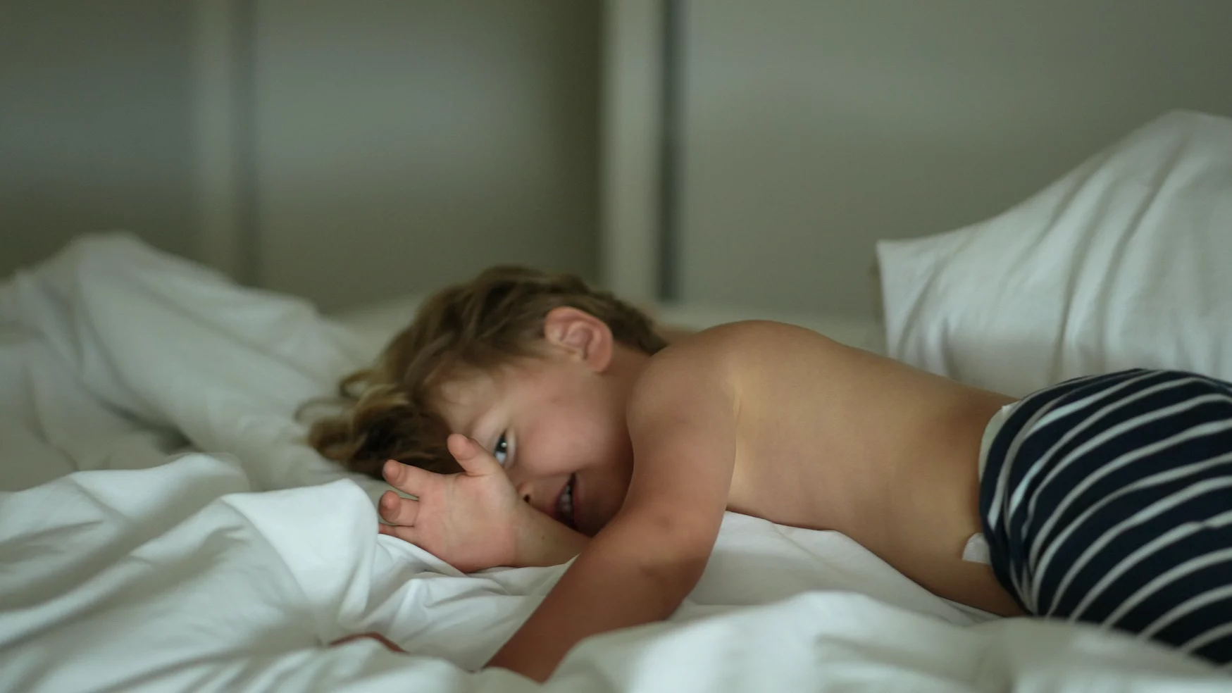 Na zdjęciu dziecko leży w pościeli