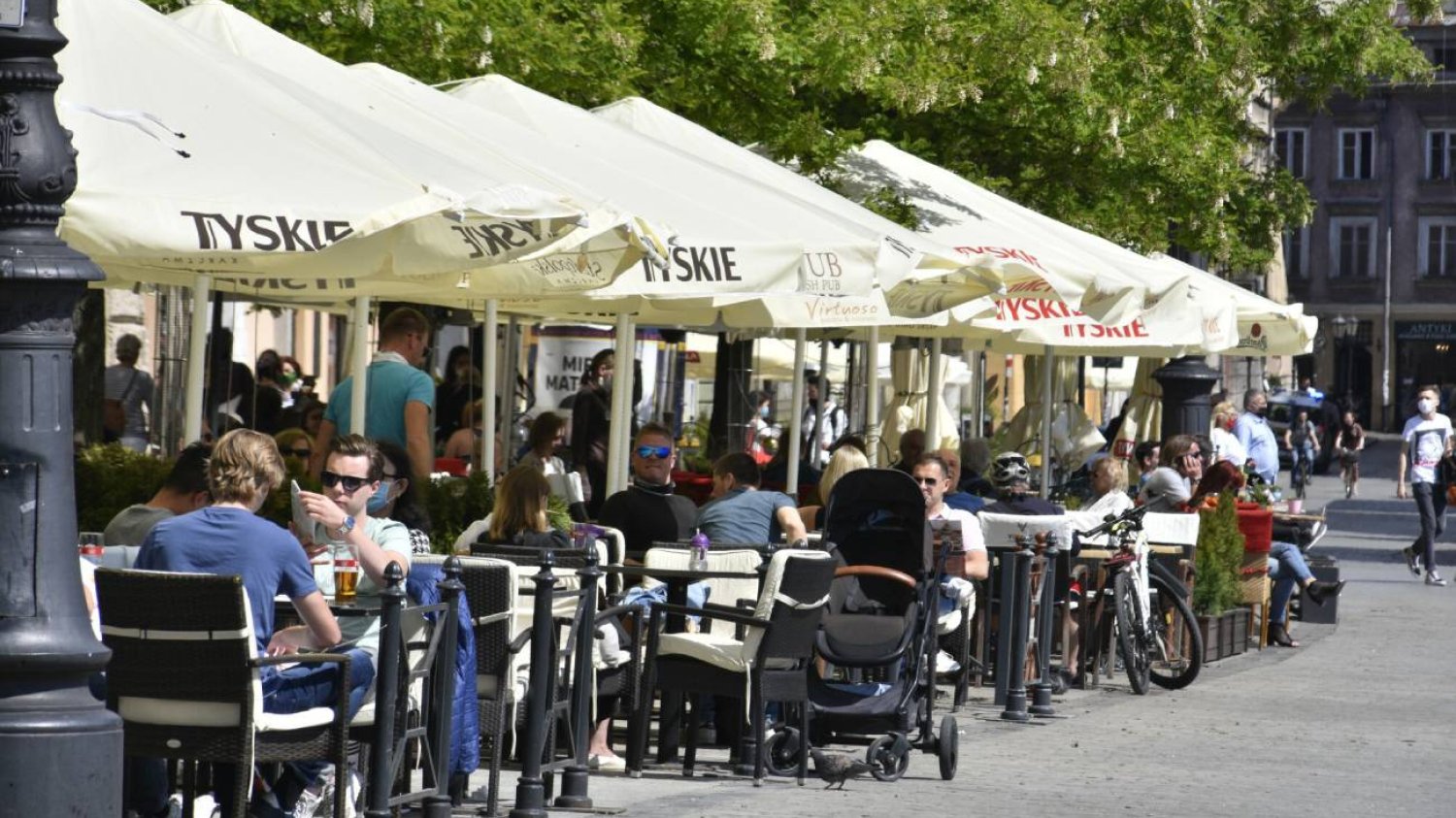 Restauracyjny ogródek, w którym przy stoliku siedzą rodzice z wózkiem.