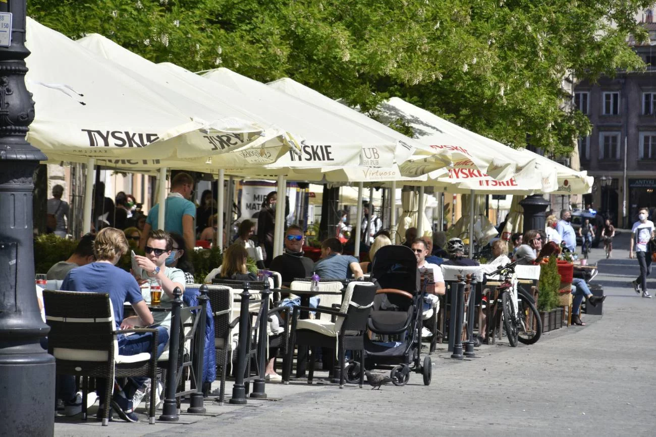 Restauracyjny ogródek, w którym przy stoliku siedzą rodzice z wózkiem.