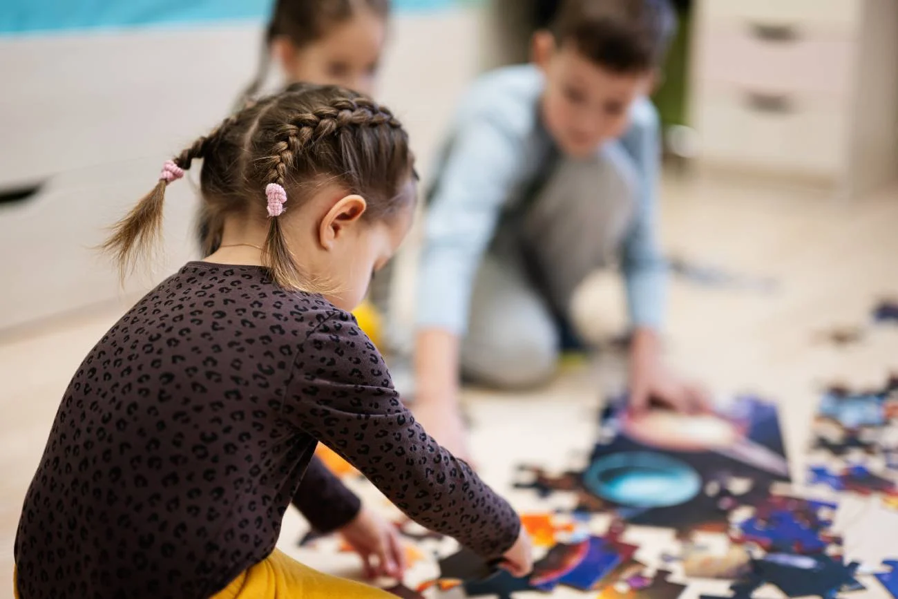 Dzieci w przedszkolu bawią się, układają puzzle.