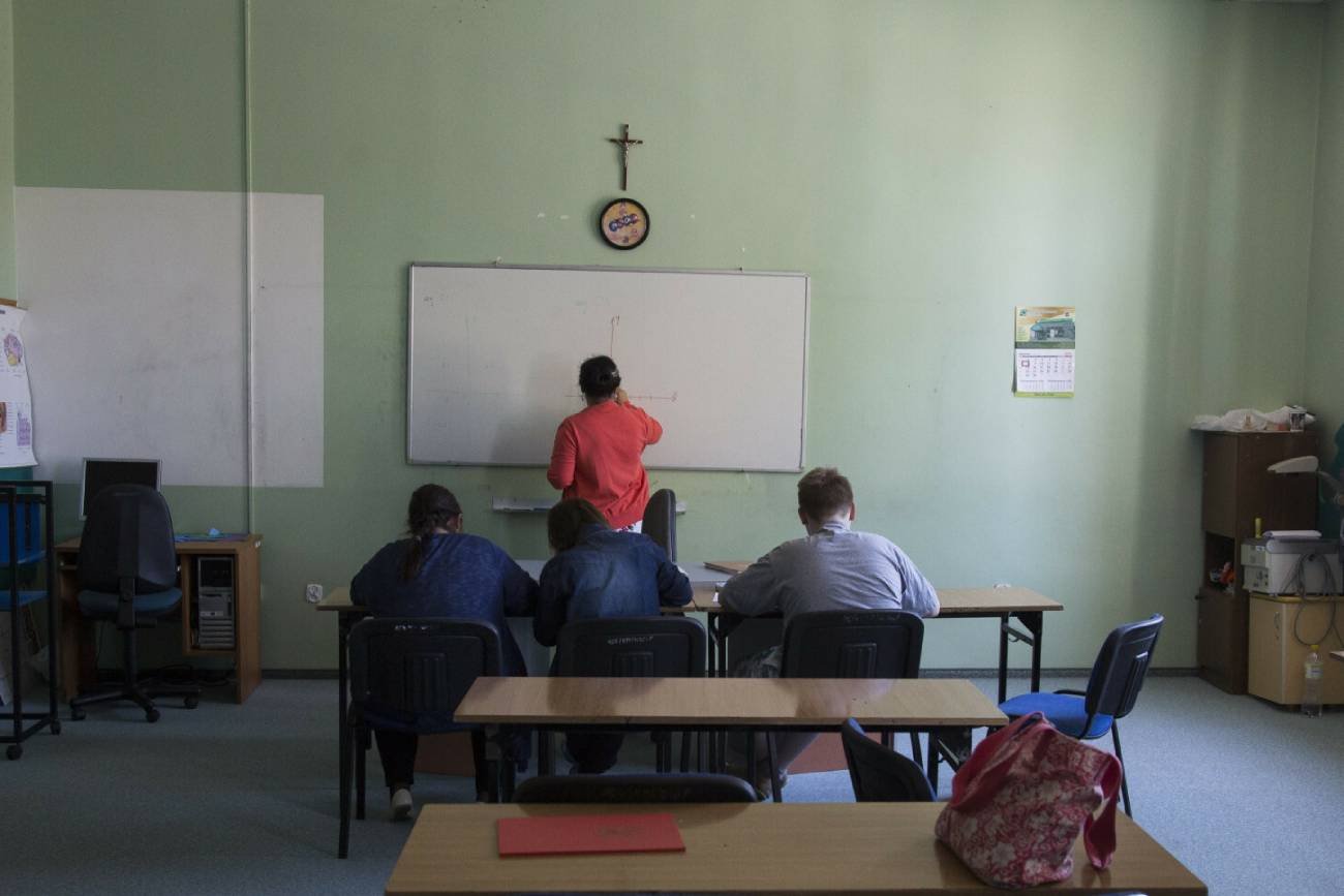 Lekcja w klasie z krzyżem na ścianie.