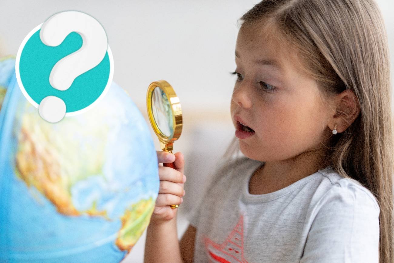 Mała dziewczynka z lupą ogląda globus.