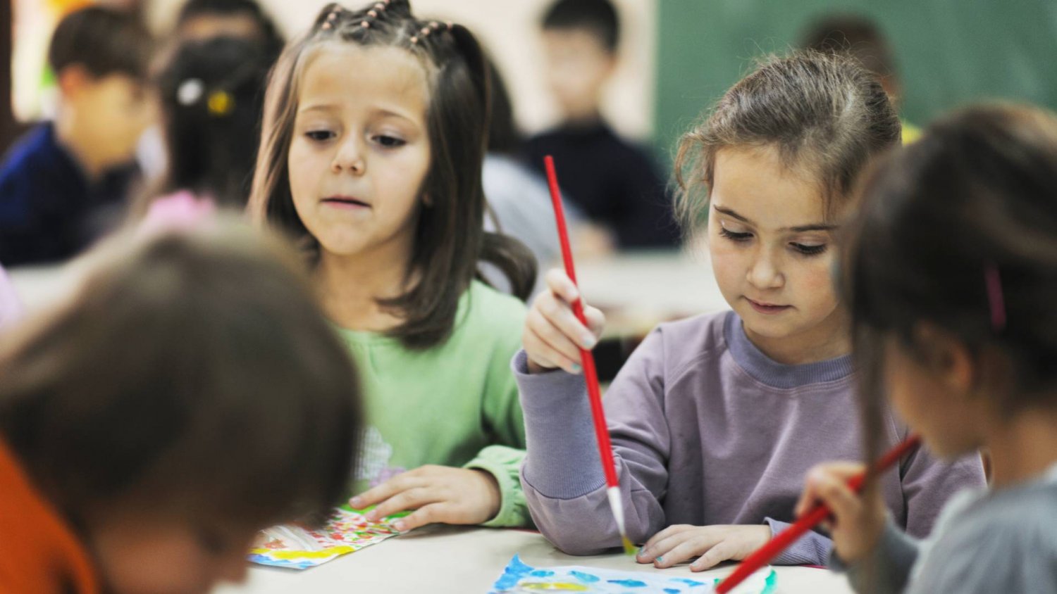 dzieci w przedszkolu przy stolikach robią prace plastyczne dzieci w przedszkolu przy stolikach robią prace plastyczne