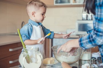 Mały chłopiec gotuje razem z mamą w kuchni.