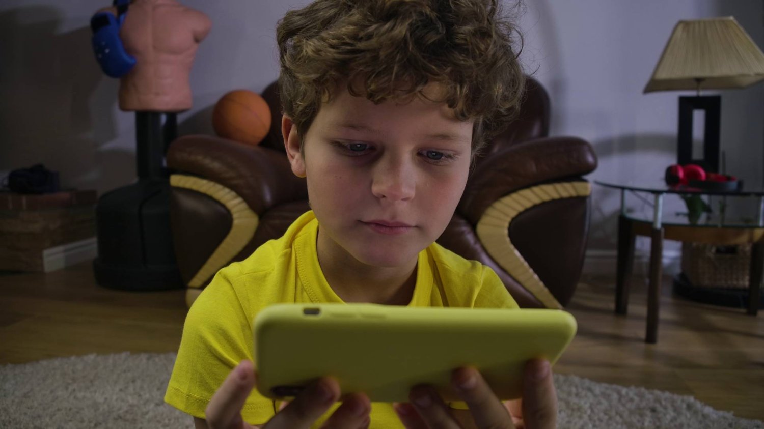 dziecko siedzi wpatrzone w ekran smartfona