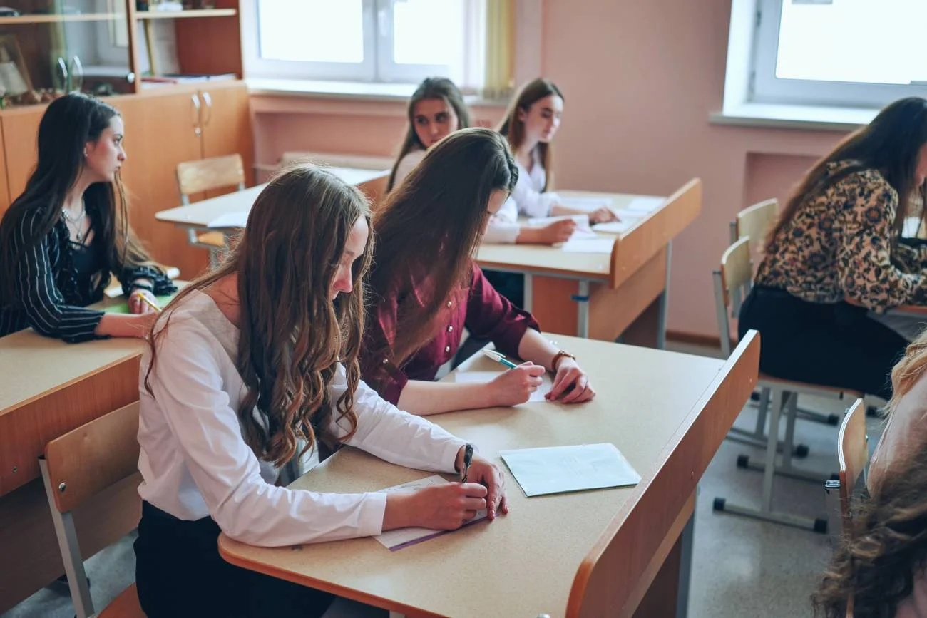 Uczniowie na lekcji siedzą w ławkach.