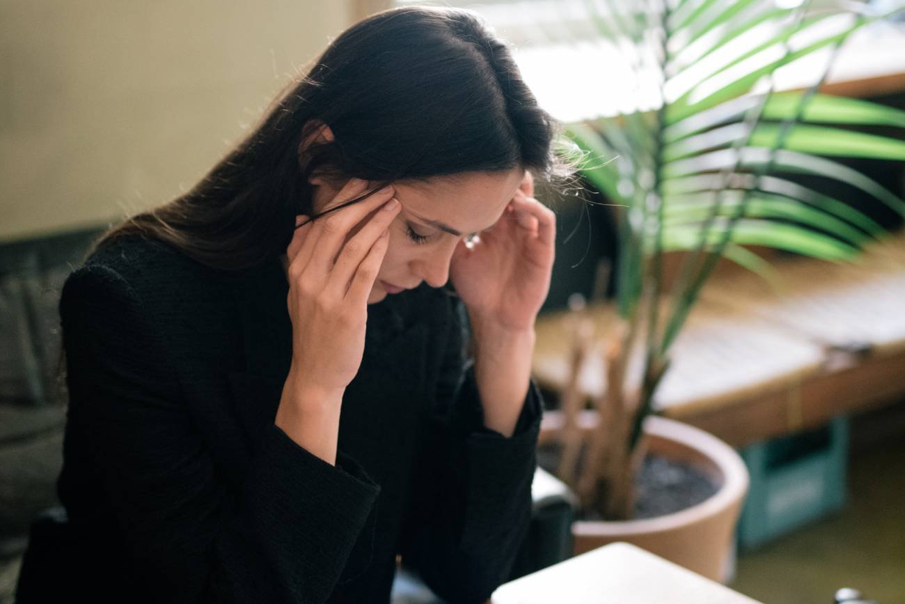 Kobieta zmęczona pracą i opieka nad dzieckiem trzyma się za głowę.