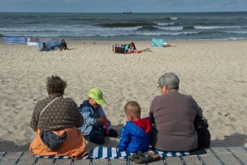 Babcie siedzą z wnukami na plaży.