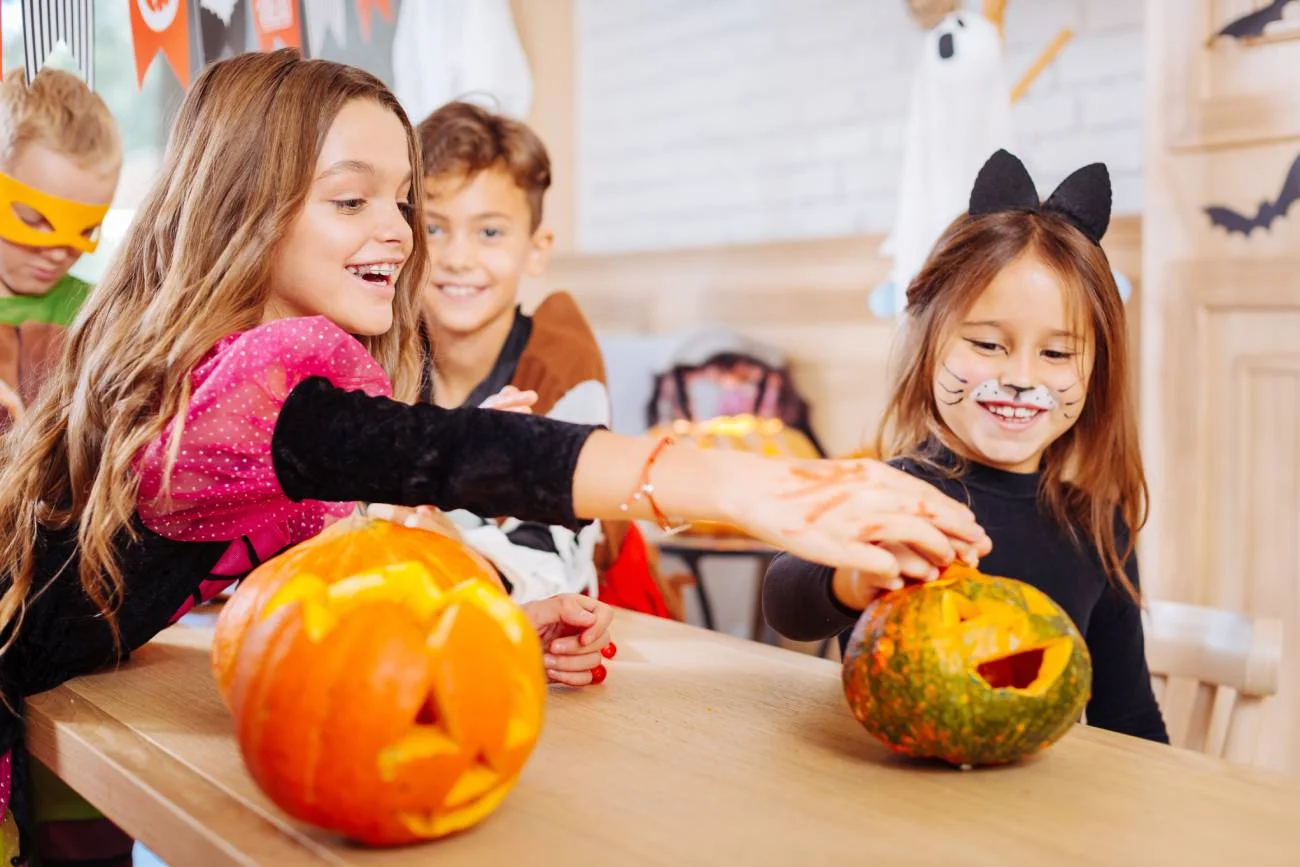 Uczniowie podczas lekcji wycinają dynię na Halloween.