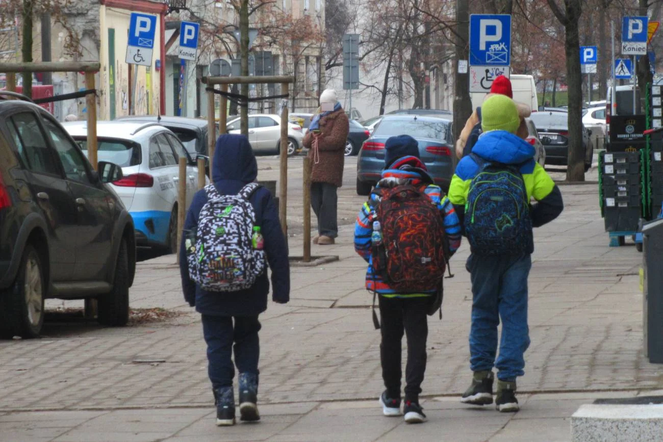 Uczniowie idą z plecakami do szkoły.