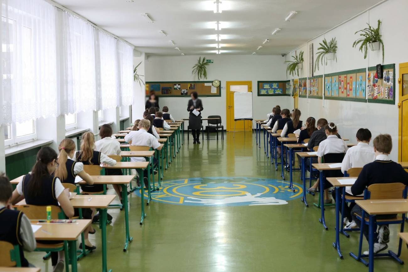 Uczniowie w ławkach przed egzaminem ósmoklasisty.