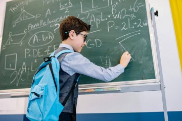 Uczeń rozwiązuje zadania matematyczne na tablicy w klasie.