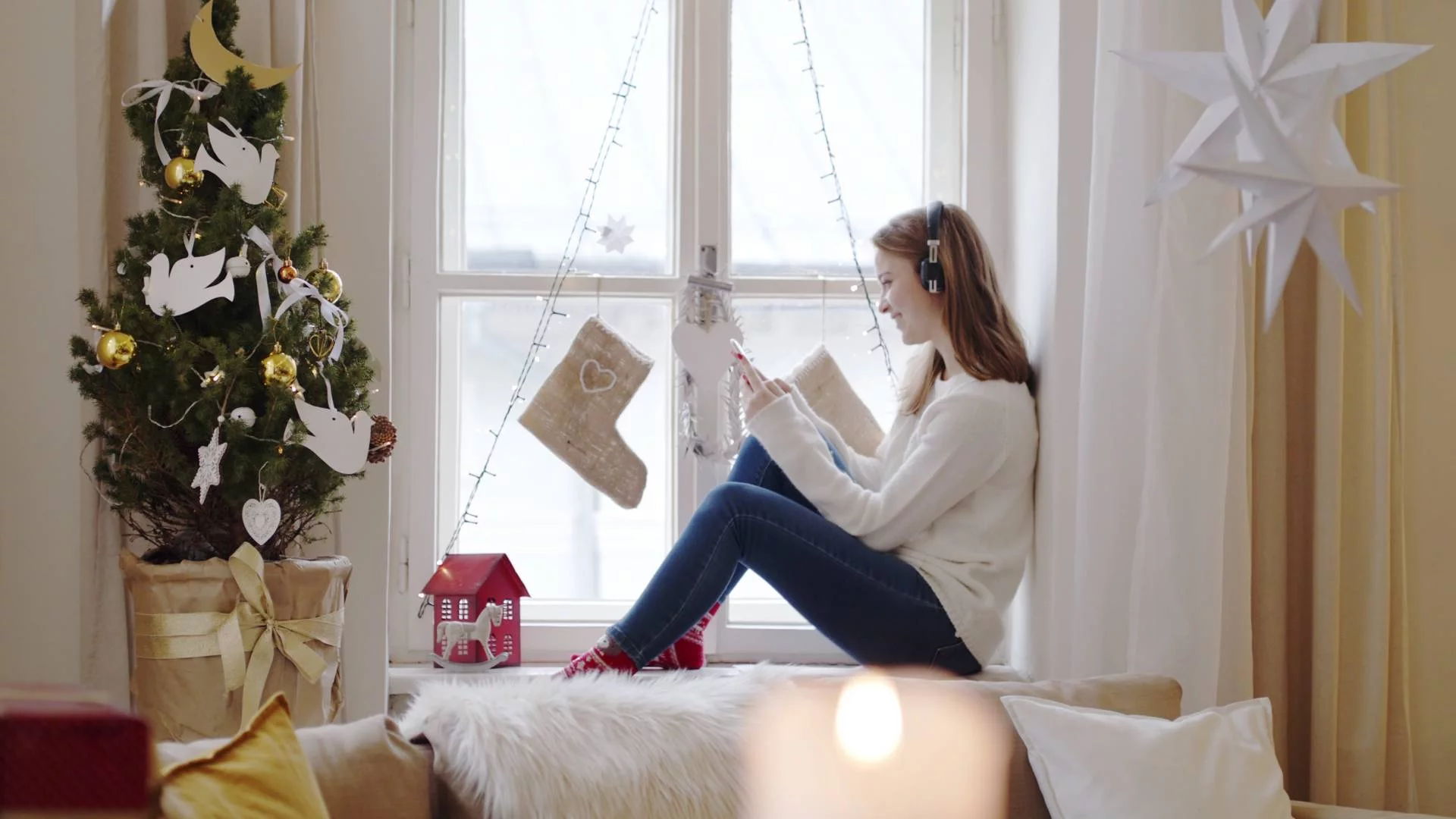 kobieta odpoczywa, słuchając muzyki i czytając książkę w domu udekorowanym na święta kobieta odpoczywa, słuchając muzyki i czytając książkę w domu udekorowanym na święta