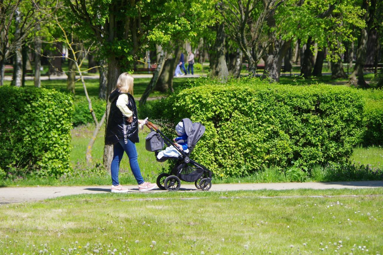 Babcia z dzieckiem w wózku na spacerze.