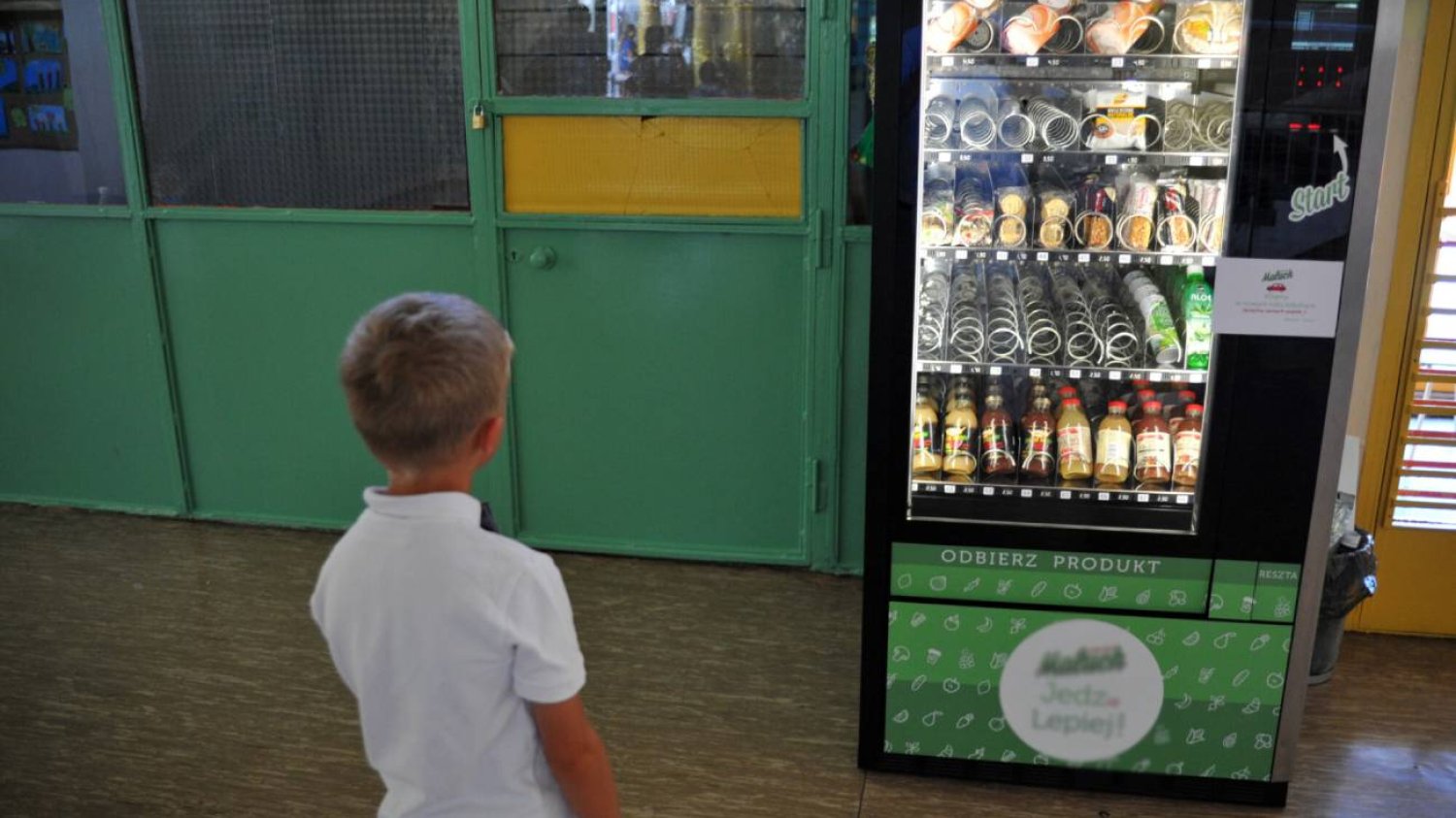 Chłopiec stoi na szkolnym korytarzu przed automatem. Chłopiec stoi na szkolnym korytarzu przed automatem.