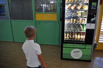 Chłopiec stoi na szkolnym korytarzu przed automatem. Chłopiec stoi na szkolnym korytarzu przed automatem.