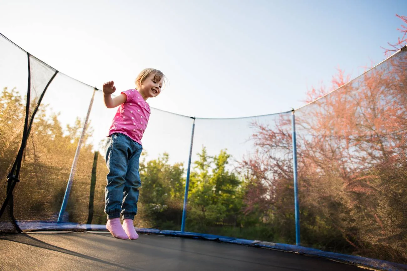 Mała dziewczynka skacze na trampolinie.