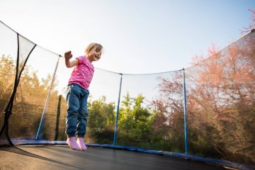 Mała dziewczynka skacze na trampolinie.