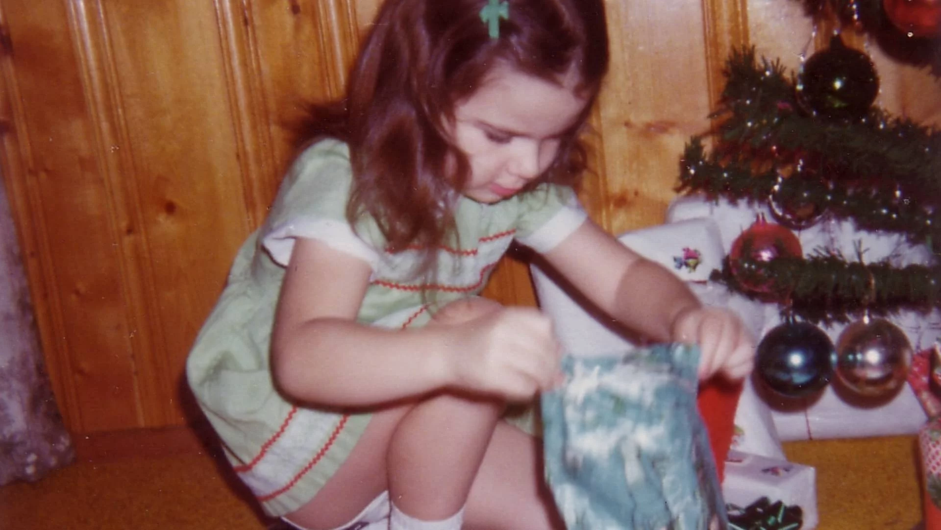 dziewczynka w latach 80. rozpakowuje prezent przy choince dziewczynka w latach 80. rozpakowuje prezent przy choince