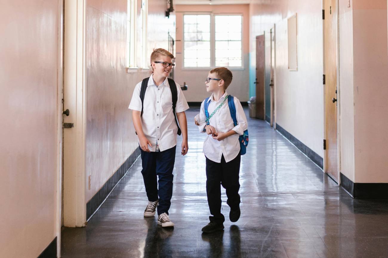 Uczniowie idą szkolnym korytarzem.
