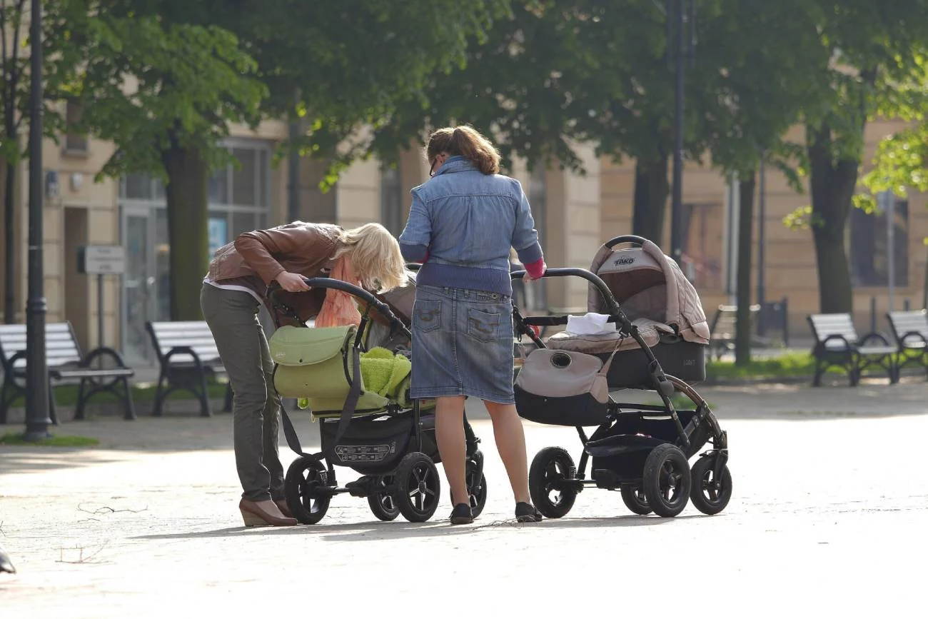 Matki spacerują z wózkami po mieście.