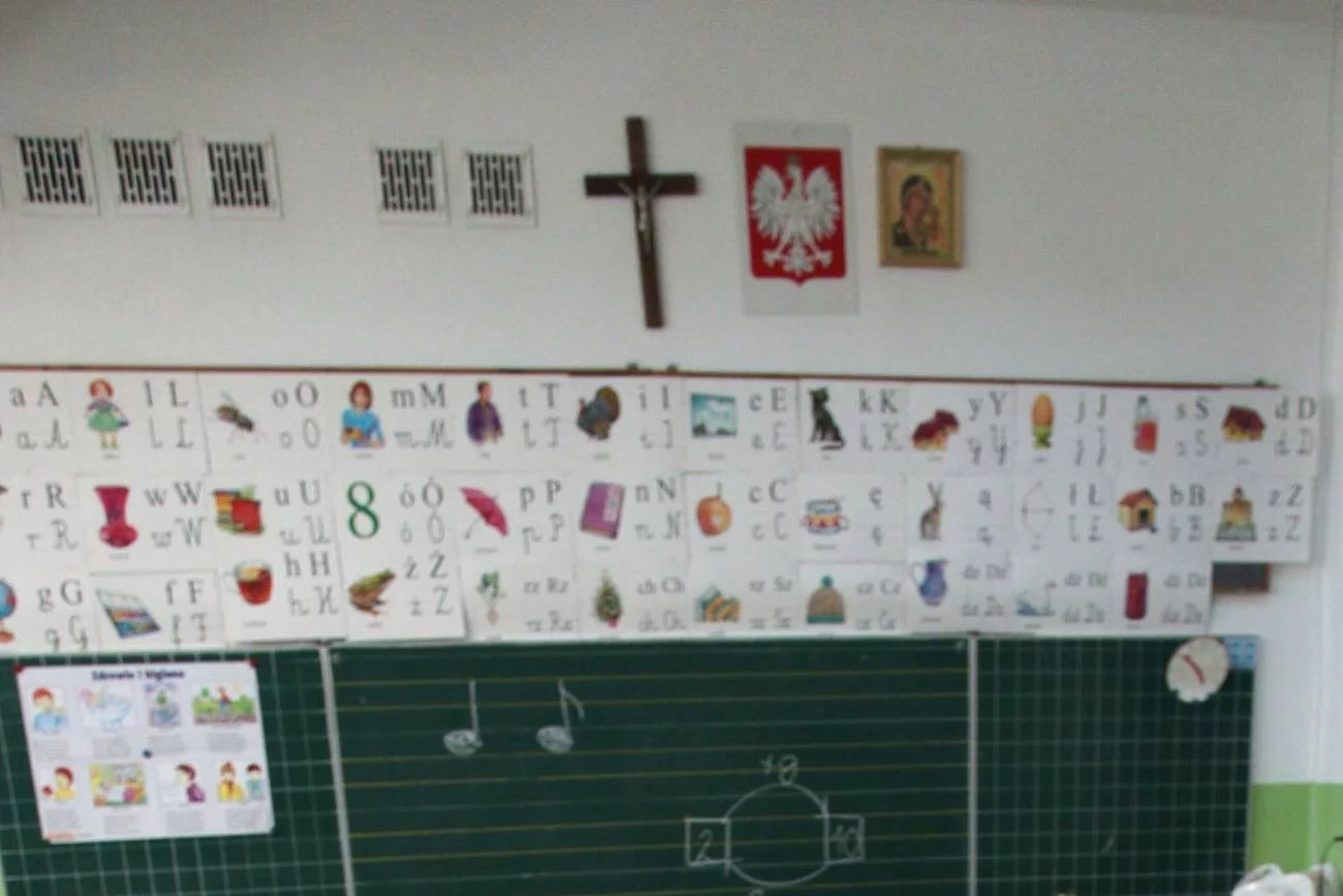 Klasa w szkole z krzyżem katolickim na ścianie.