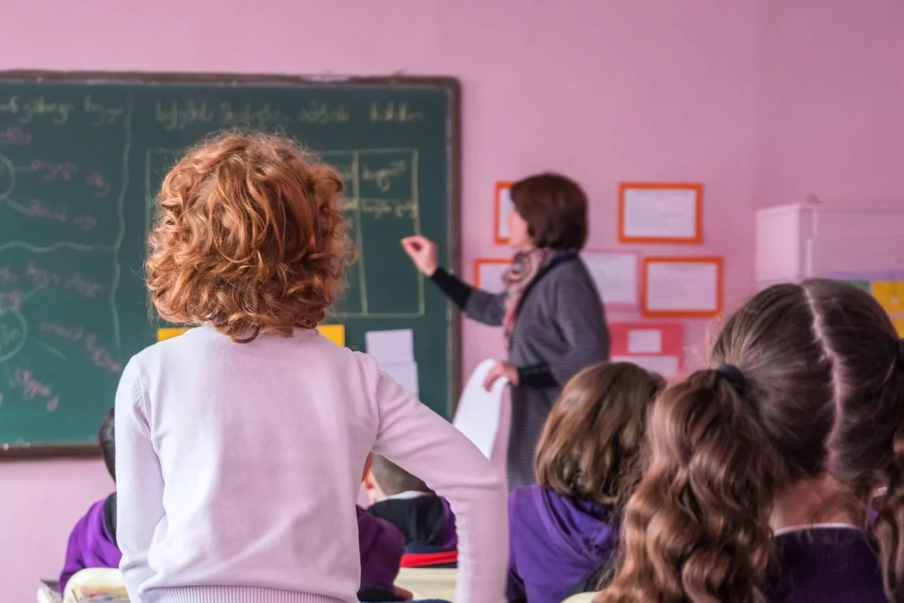 Nauczycielka prowadzi lekcję, a uczeń odpowiada na pytanie.