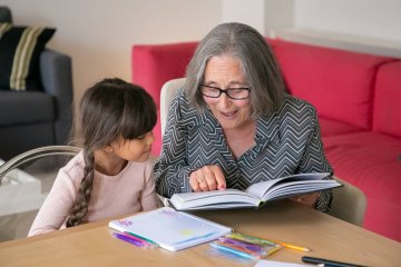 Babcia z wnuczką oglądają i czytają książkę.