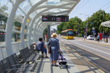 Starsza kobieta czeka na tramwaj w Warszawie.