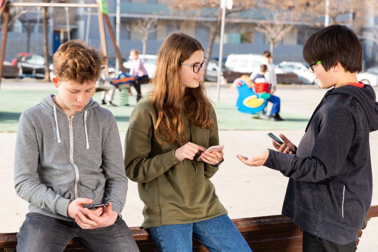 Nastolatki z telefonami przeglądają social media.
