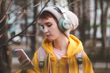Nastoletnia dziewczynka patrzy w ekran telefonu.