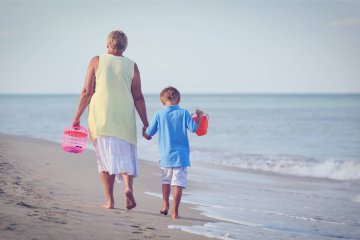 Babcia i wnuk spacerują nad brzegiem morza.