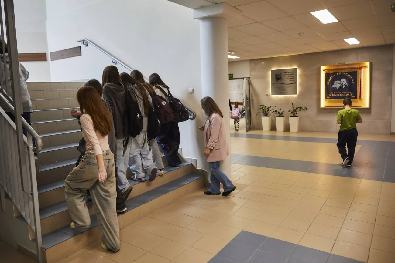 uczniowie idą szkolnym korytarzem