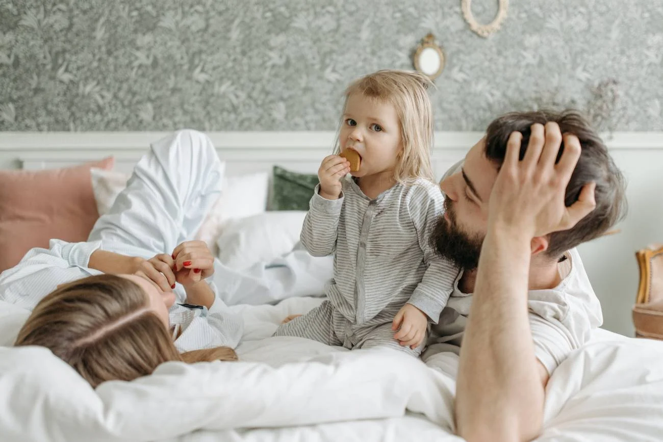 Rodzice bawią się na łóżku z dzieckiem.